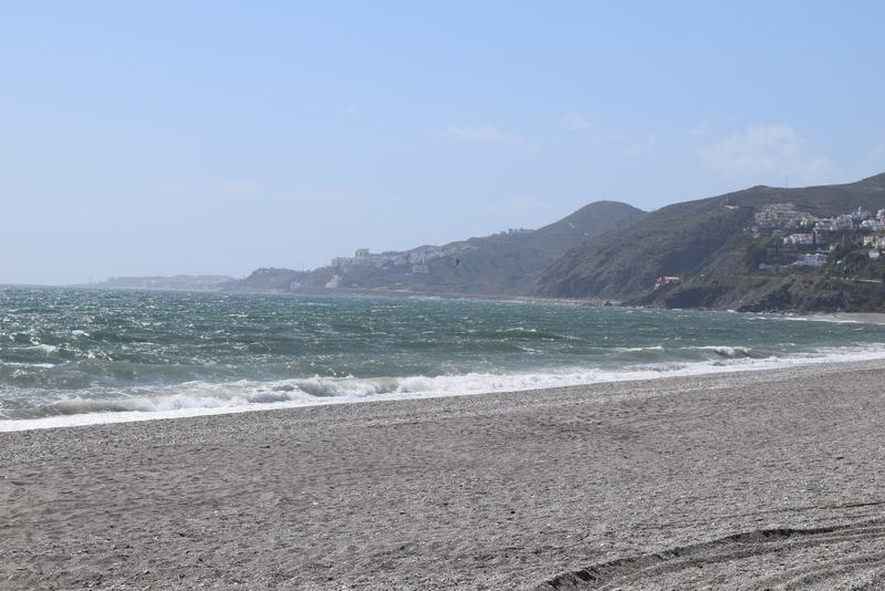 La plage d’El Playazo, à Nerja, longue et de sable sombre, avec la côte et les montagnes au fond