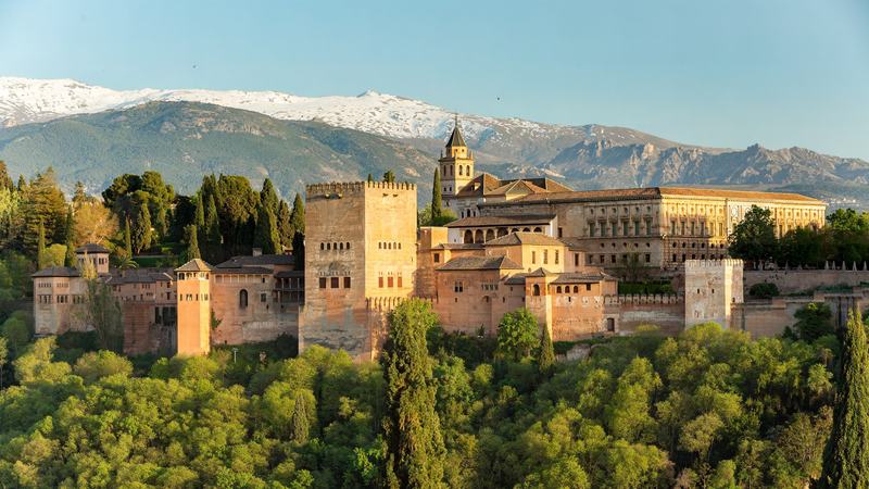 L’Alhambra au coucher du soleil vue du mirador de San Nicolás, au-dessus du bois, avec la Sierra Nevada enneigée au fond