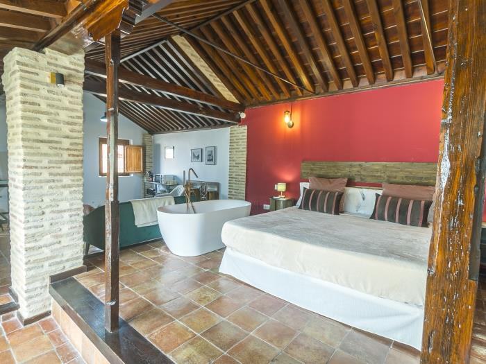 La Crimson Red Suite, mansardée, avec son lit double, son mur rouge et sa baignoire îlot