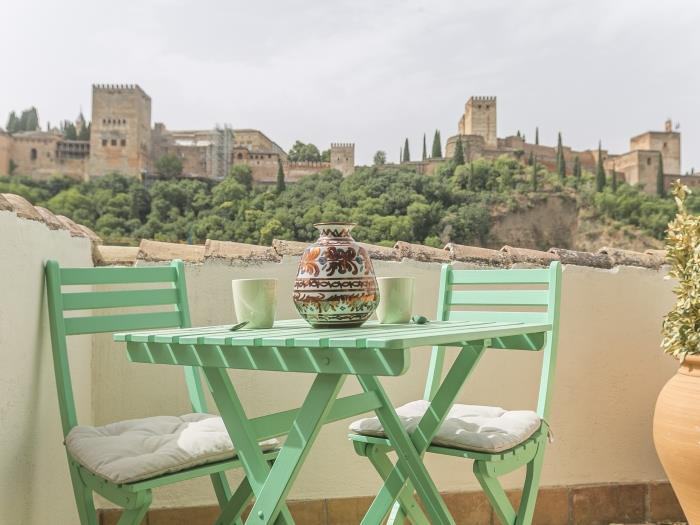 Une table et deux chaises vertes face à l’Alhambra, aux Suites Dreams Granada, dans l’Albaicín