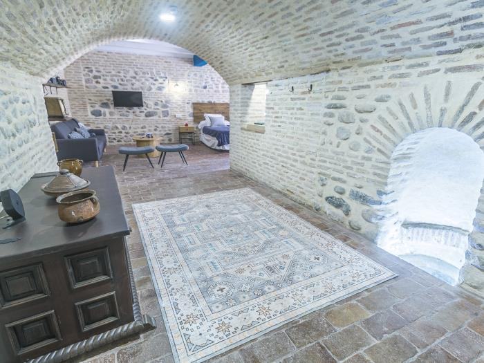 La Blue Room Cueva, une ancienne cave voûtée aux murs de pierre, transformée en suite avec salon et tapis